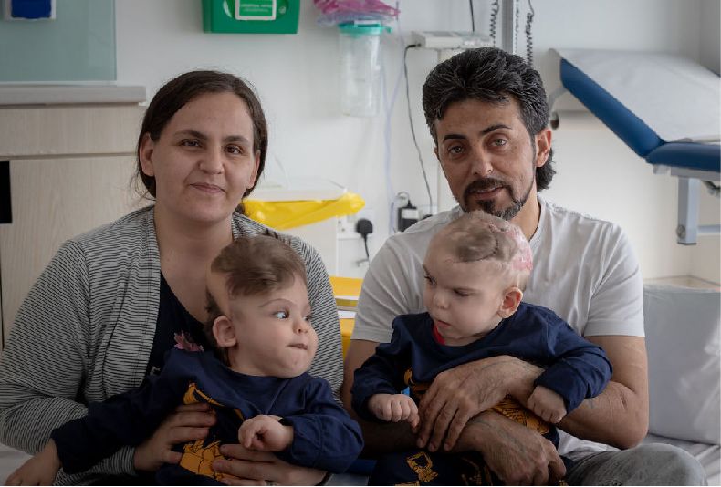 Yigit and Derman's parents hold them post-operation in the hospital.